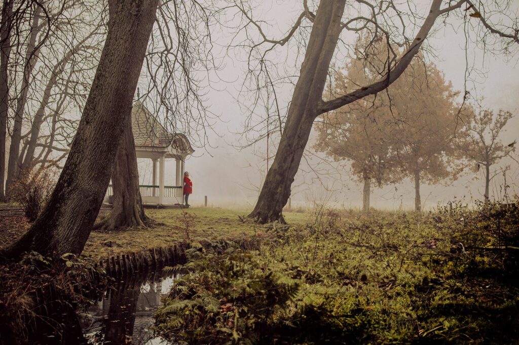 Frau im roten Kleid im Nebel vor Pavillon im Bürgerpark Bremen