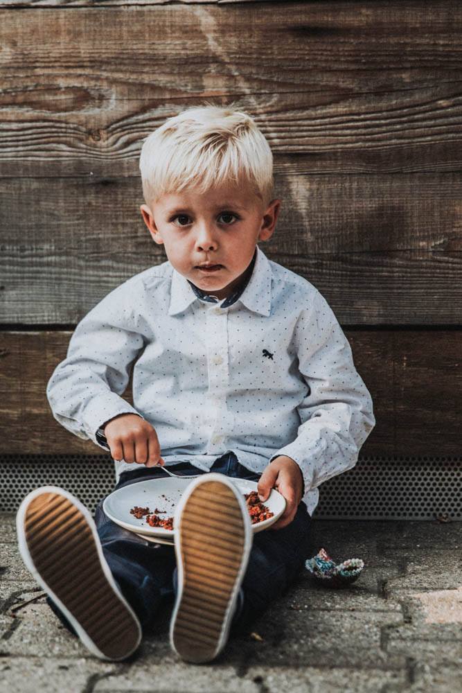 Junge sitzt mit Essen auf dem Boden.